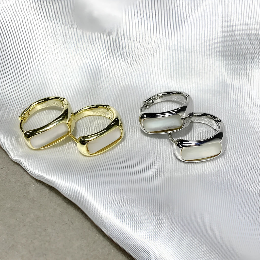 Four pairs of round buckle earrings in gold and silver metal finish on white background