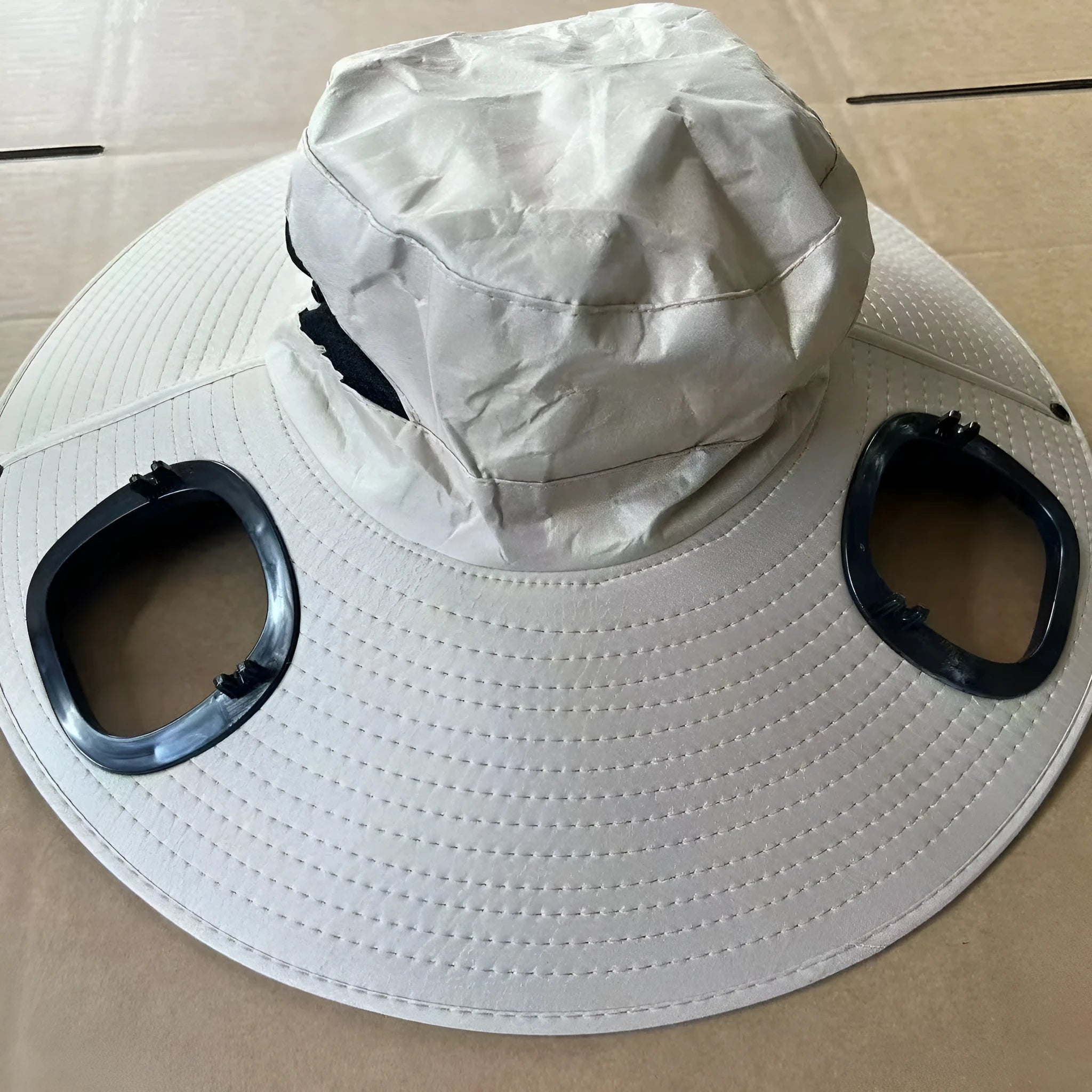 Man wearing a grey wide-brim cap with a built-in solar cooling fan on the front, adjustable headband visible.