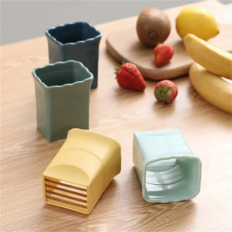 Green stainless steel cup fruit slicer with sliced strawberries on a light background