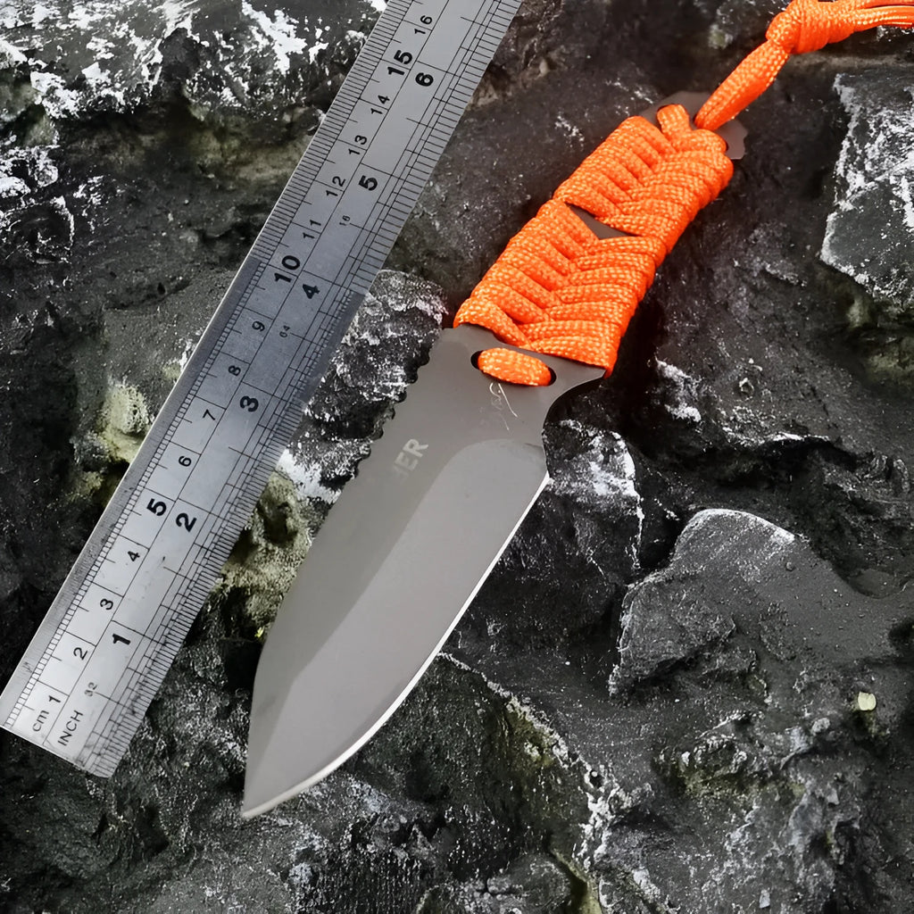 Straight blade outdoor survival knife with binding rope handle next to ABS plastic sheath