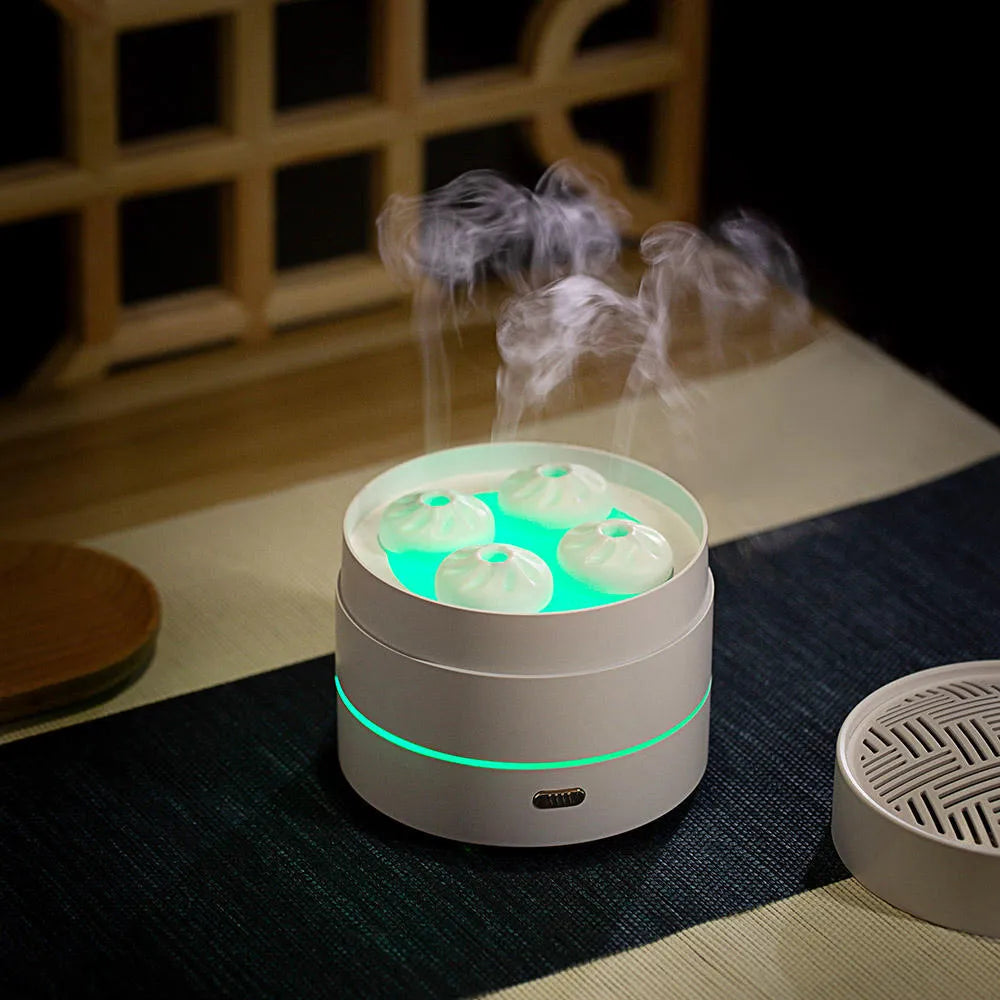 White ultrasonic aroma diffuser with four steam nozzles and LED light on a wooden table
