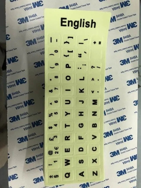 Yellow PVC sheet of glow-in-the-dark keyboard stickers for Arabic, Thai, Hebrew, French, Italian, and German layouts.