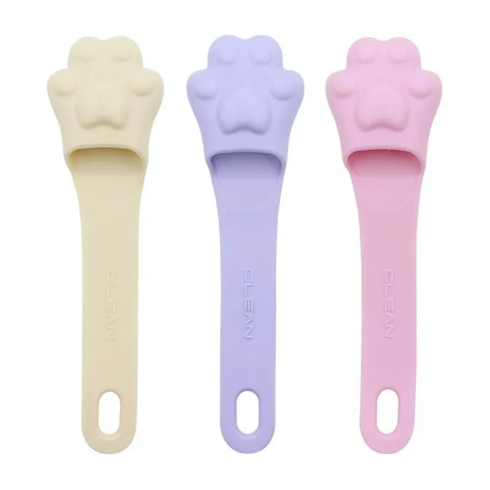 Silicone fingertip toothbrush for pets in pink, purple, and yellow, shown on a finger.