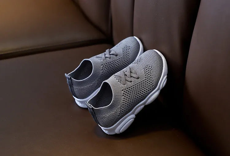 Children's white fabric lazy shoe with a non-slip rubber sole, shown on a foot.