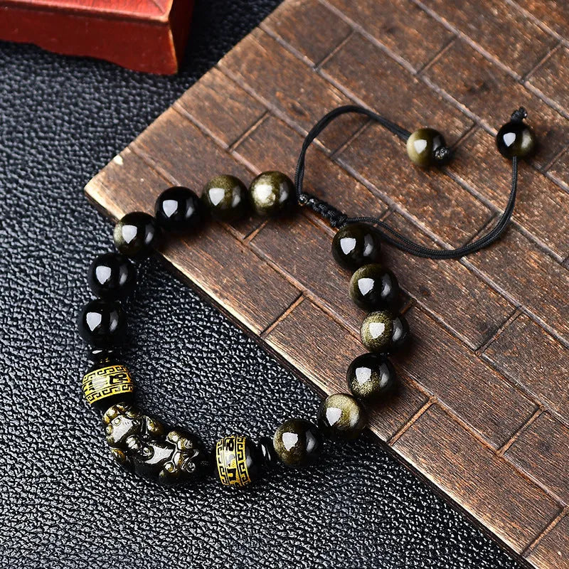 Golden obsidian bead Pi Xiu bracelet with hand-woven design on a wrist.
