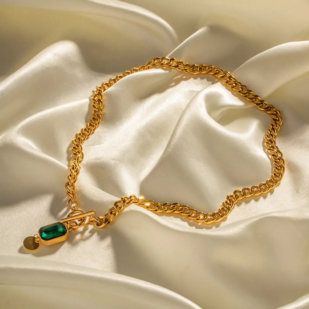 Gold electroplated geometric round pendant necklace with emerald zircon accents on Cuban link chain