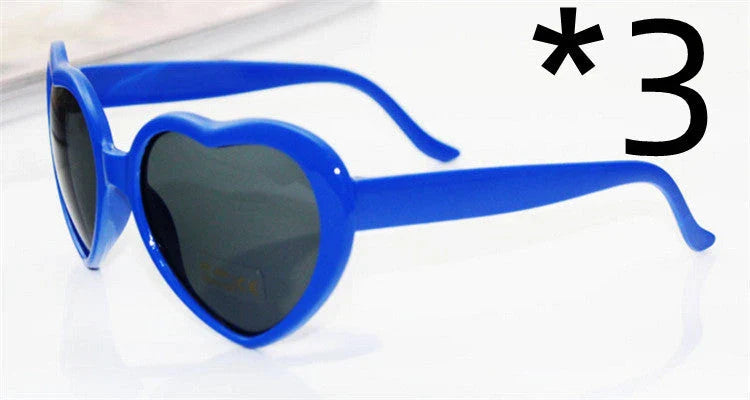 Heart-shaped glow-in-the-dark sunglasses in various vibrant colors, featuring a durable plastic frame and resin lenses for reliable UV protection.