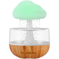 White cloud-shaped humidifier with LED night light and water droplet effect on a table.