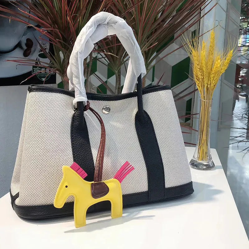 Women's canvas bucket tote bag with leather trim in black, shown with internal zip and document pockets.