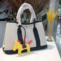 Women's canvas bucket tote bag with leather trim in black, shown with internal zip and document pockets.