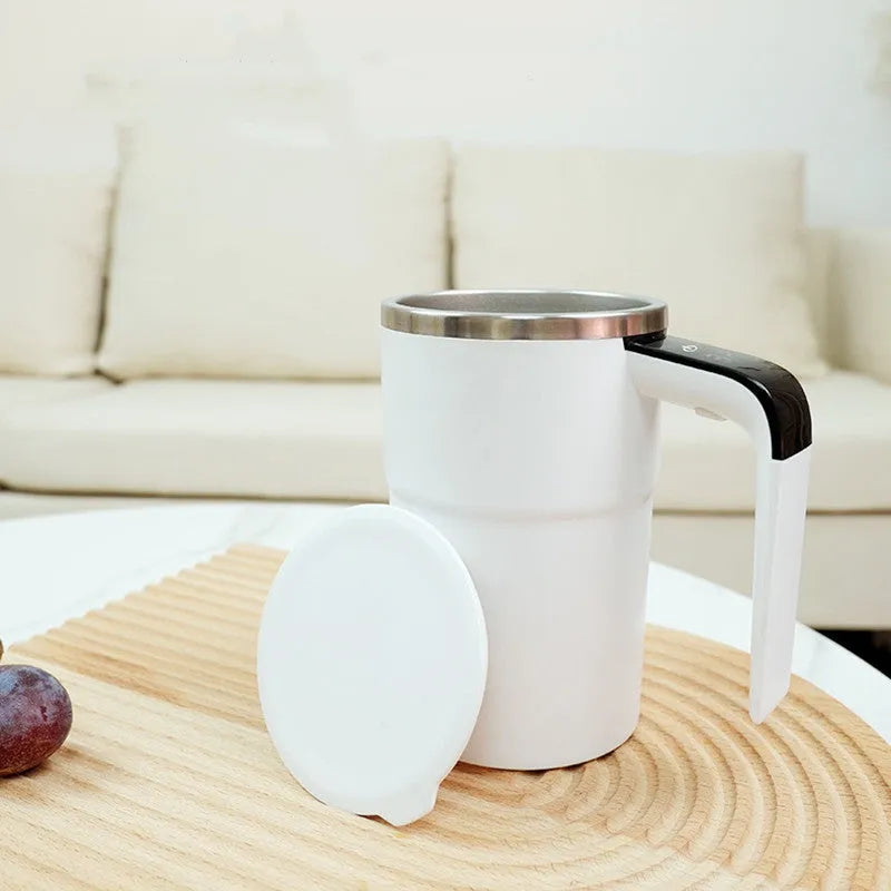 Black and white USB rechargeable electric stirring mug with LCD screen showing temperature, next to its magnetic stirrer.
