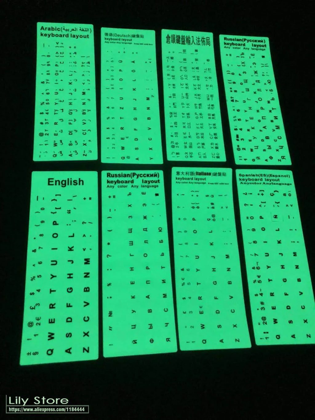 Yellow PVC sheet of glow-in-the-dark keyboard stickers for Arabic, Thai, Hebrew, French, Italian, and German layouts.