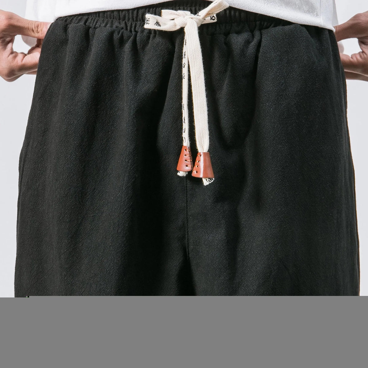 Men's cotton harem joggers in black with drawstring waist, two slant pockets, and tapered ribbed ankle.