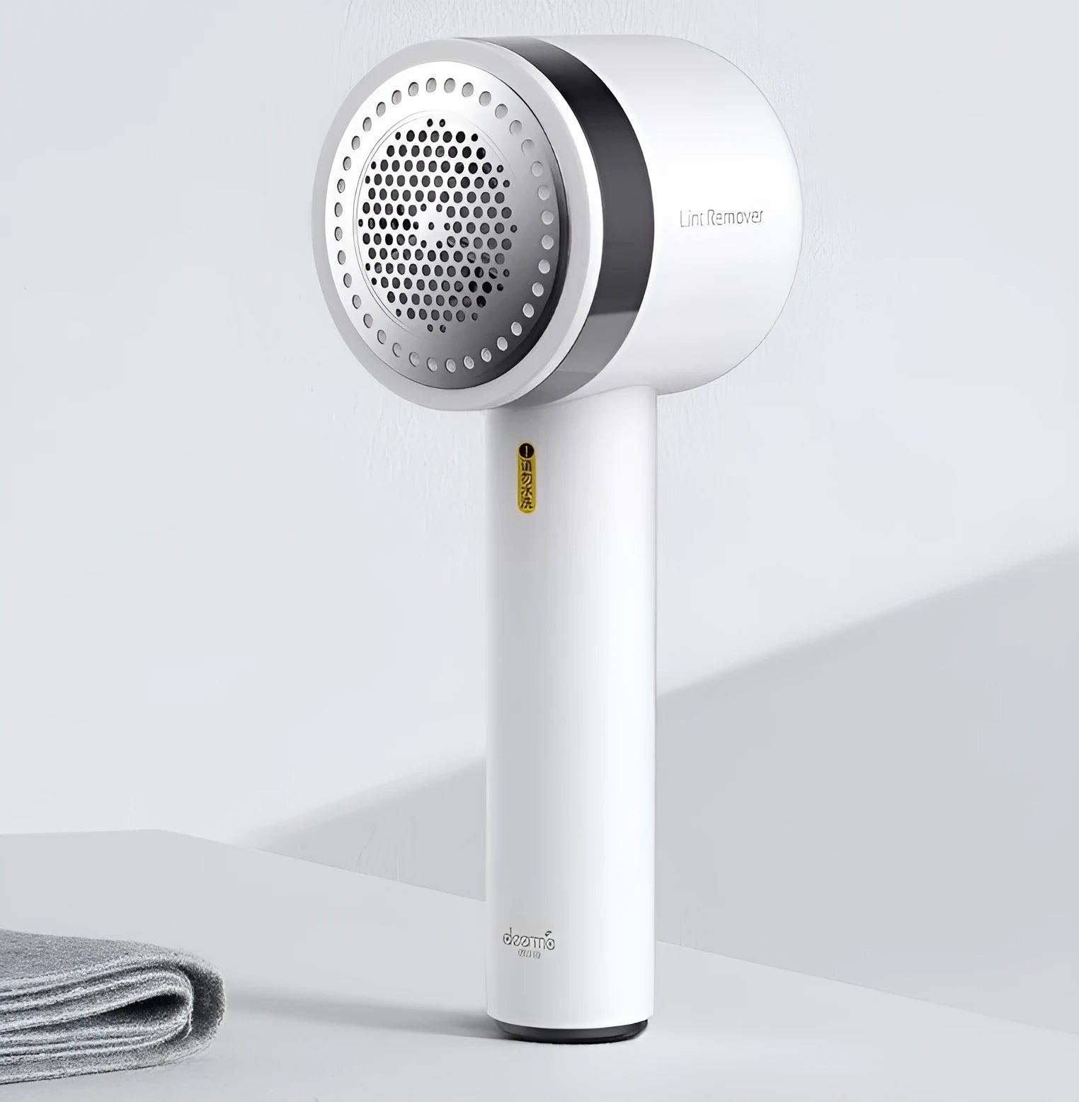 White rechargeable lint remover with hidden hair collection container and detachable three-blade head on white background