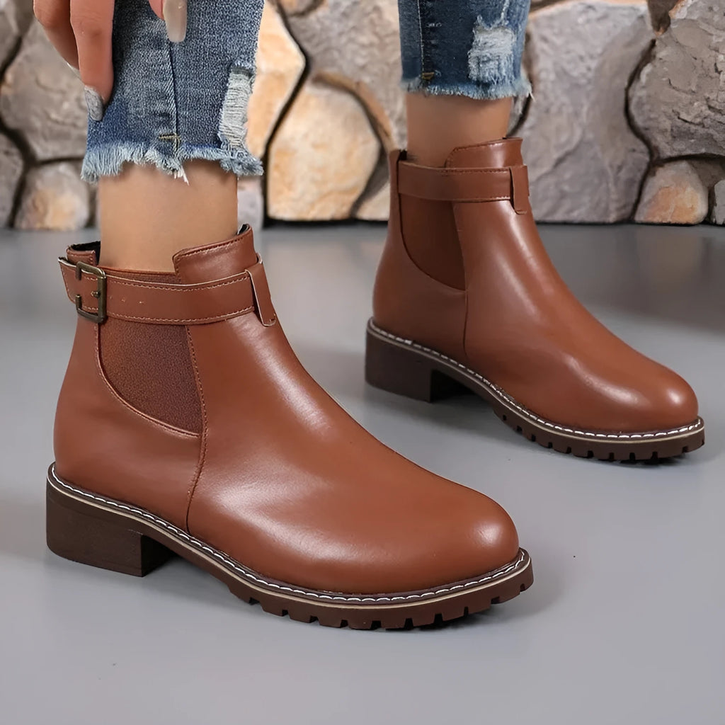 Women's round toe ankle boots with a belt buckle detail on the upper, shown in black.