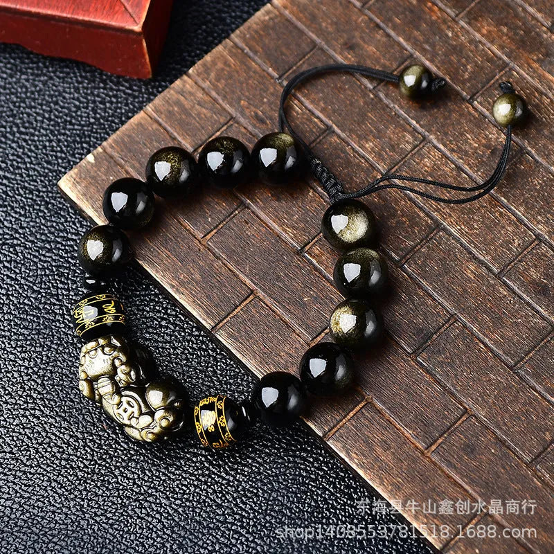 Golden obsidian bead Pi Xiu bracelet with hand-woven design on a wrist.