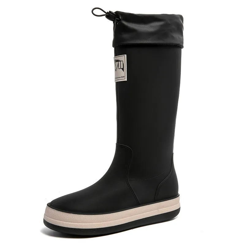 A pair of high tube PVC rain boots in a solid colour, shown on a non-slip sole.