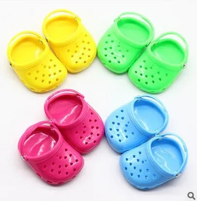 A pair of small plastic doll beach slippers in assorted colours: blue, red, yellow, and green.