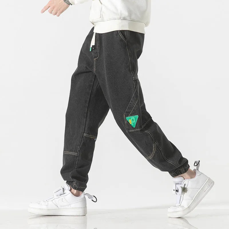 Man wearing loose-fit tapered trousers in grey, showing the mid-waist and tapered leg design.