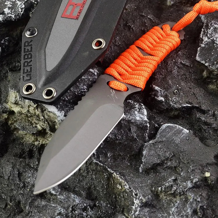Straight blade outdoor survival knife with binding rope handle next to ABS plastic sheath
