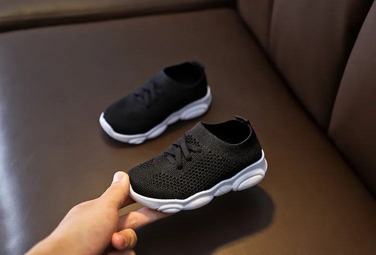 Children's white fabric lazy shoe with a non-slip rubber sole, shown on a foot.