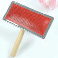Red pet needle comb dog grooming comb with wooden handle and stainless steel plate on a neutral background