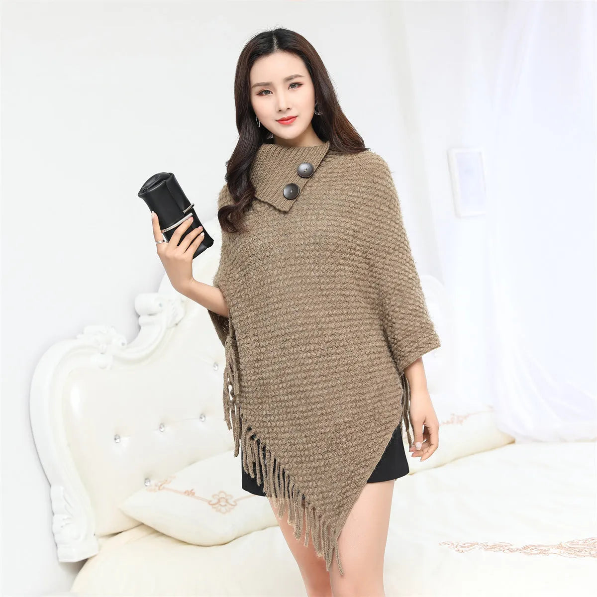 Sleeveless knitted cloak shawl with dot pattern, shown in apricot colour