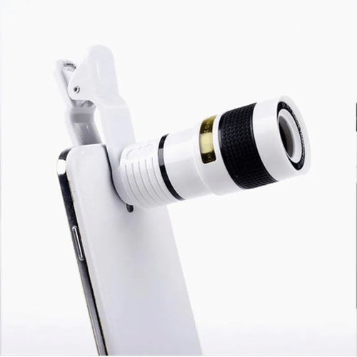 A black 12X phone telescope lens next to a universal mounting clip and cleaning cloth on a table.