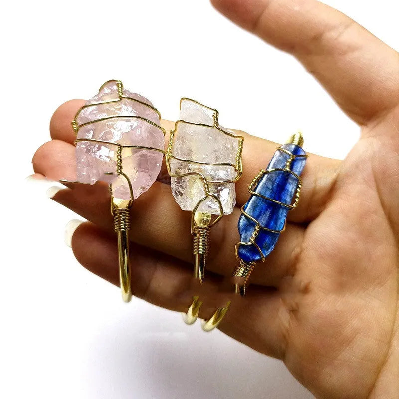 Rough natural crystal bracelet with gold winding geometric design on a wrist.