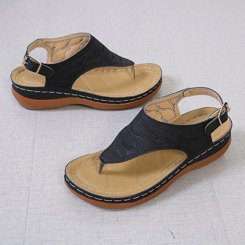 Women's beige wedge heel flip flop sandals with an adjustable buckle strap on a wooden deck.