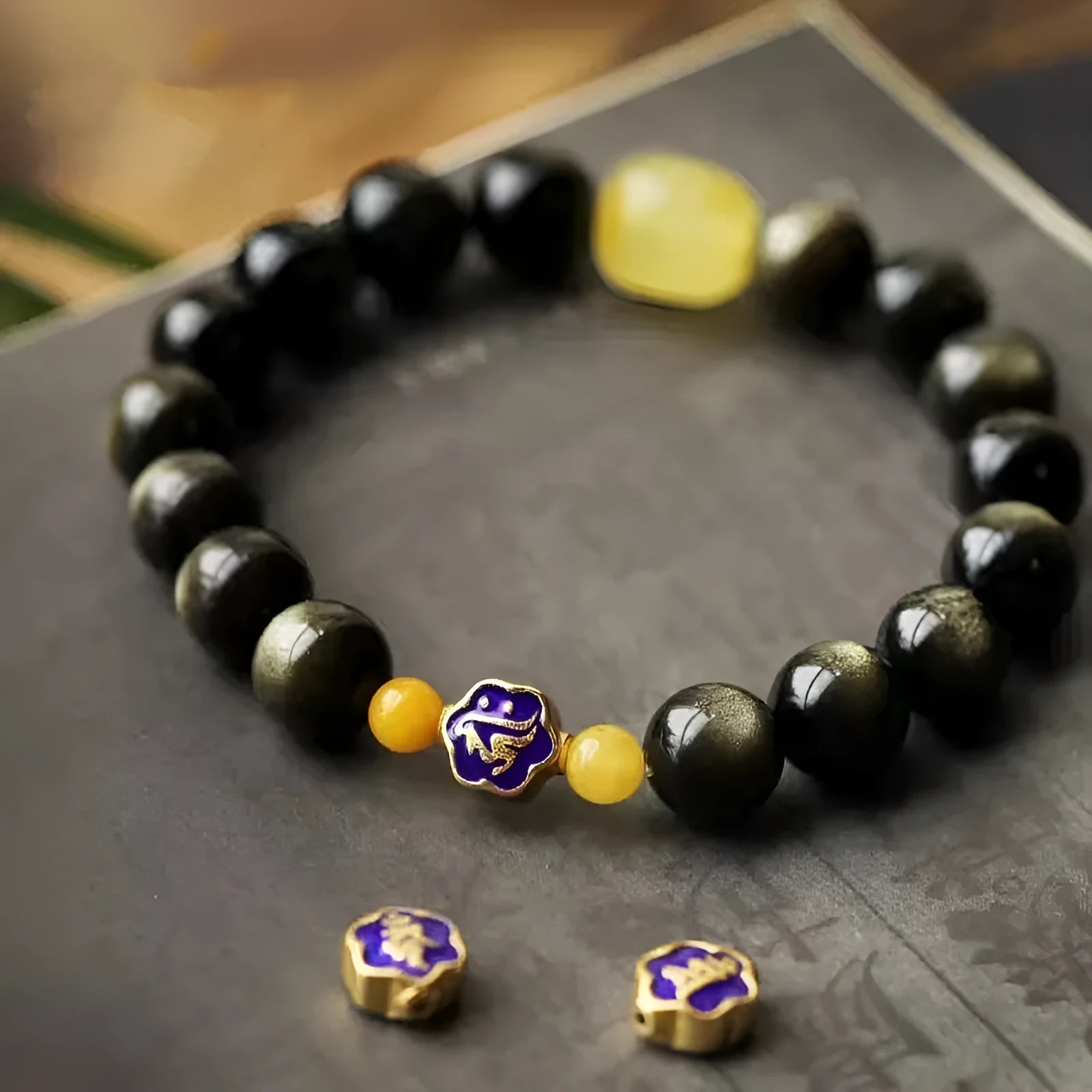 Handmade golden obsidian bracelet with geometric beads and zodiac charm on wrist.