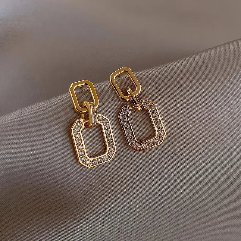 Pair of geometric alloy ear studs with electroplated finish on white background
