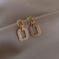 Pair of geometric alloy ear studs with electroplated finish on white background