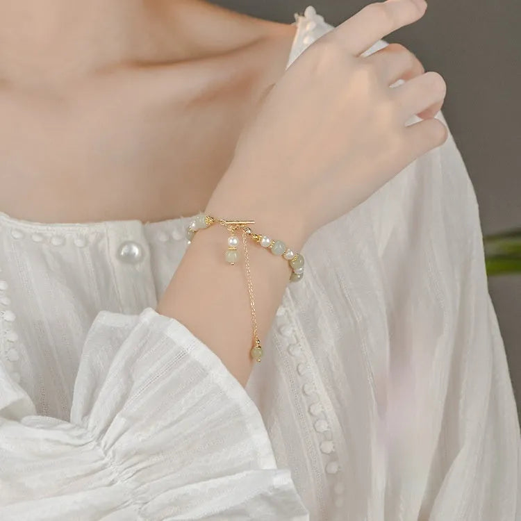 Women's bracelet with a round Hetian jade bead, pearl pendant, and gold-colour alloy clasp.
