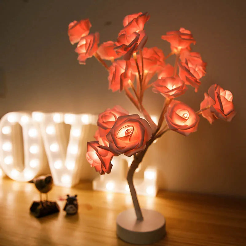 White and red rose flower LED table lamp with bonsai tree and garland lights on a table.