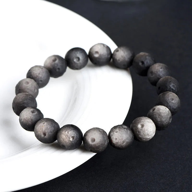 Natural obsidian crater ball bracelet with textured beads in silver stone meteorite finish.