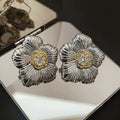 Close-up of retro textured gardenia stud earrings in two-tone copper with floral petal detail.