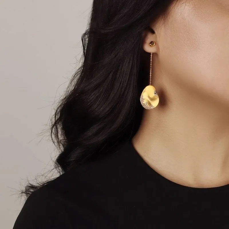 A pair of asymmetric gold-plated flower earrings with zircon detail, shown in silver and gold colour options.
