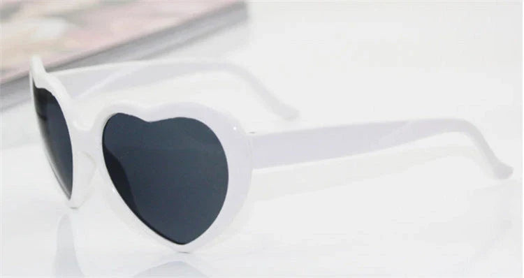 Heart-shaped glow-in-the-dark sunglasses in various vibrant colors, featuring a durable plastic frame and resin lenses for reliable UV protection.