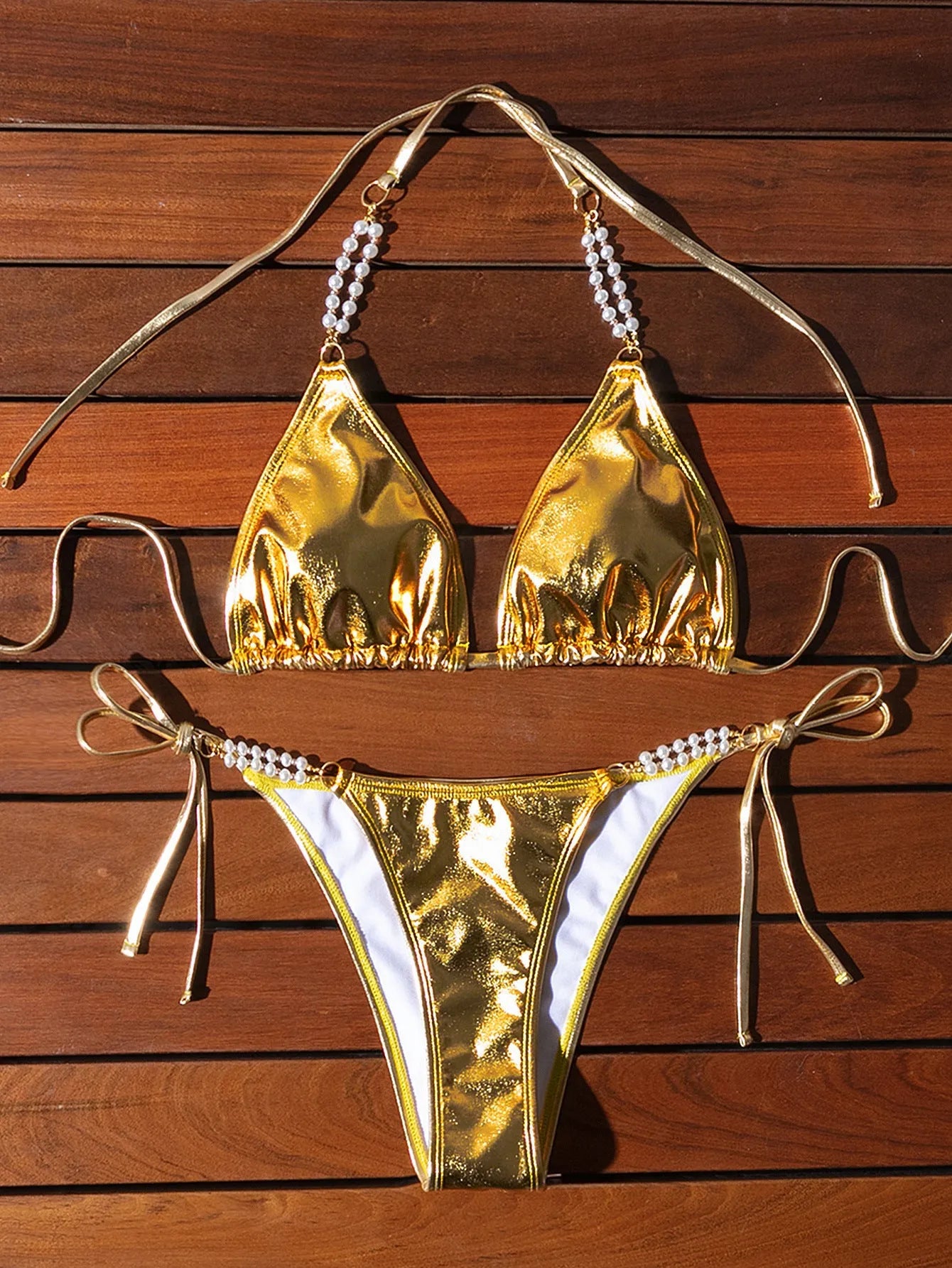 Gold halter neck bikini top with lace-up front and pearl chain, paired with brief-style bottoms