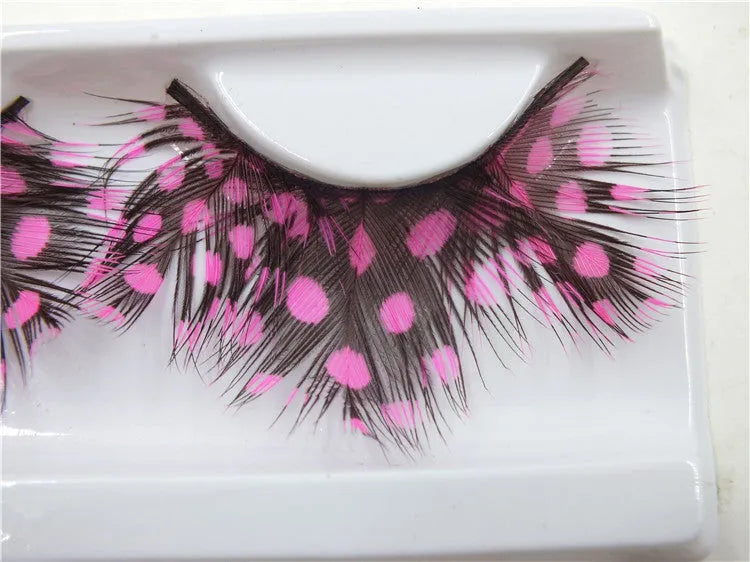 Handmade two-tone feather false eyelashes on a flat surface showing colour matching and feather texture