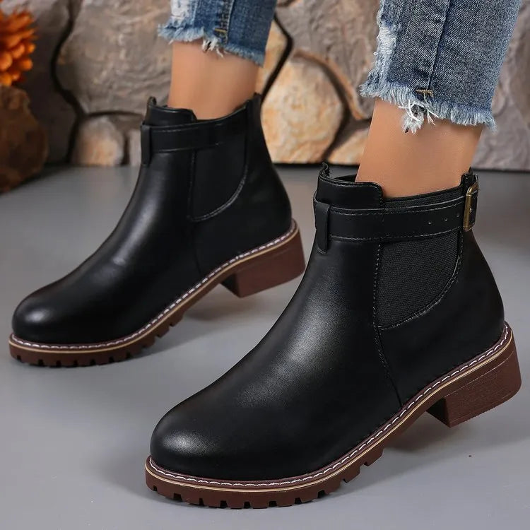 Women's round toe ankle boots with a belt buckle detail on the upper, shown in black.