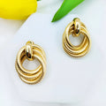 Geometric ring embossed twisted metal stud earrings in gold colour on a plain background