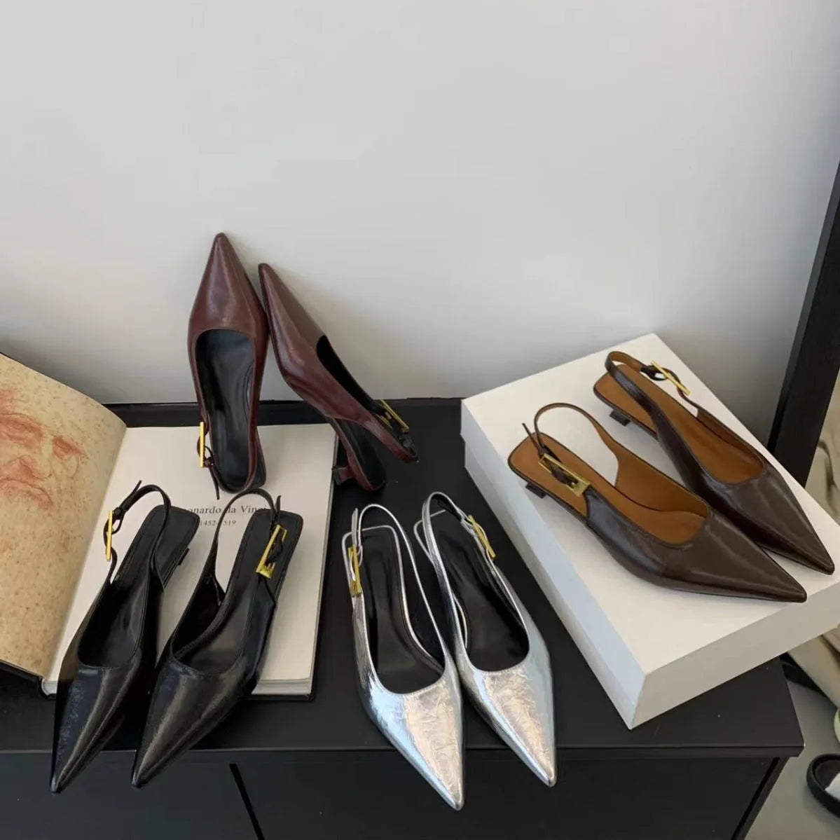 Black pointed toe low heel women's shoes with an ankle strap and rubber sole.