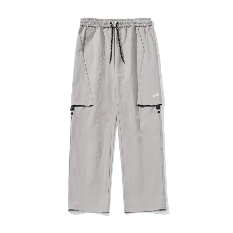 Men's loose-fit nylon casual trousers in black, grey green, or greige, with adjustable split and breathable fabric.