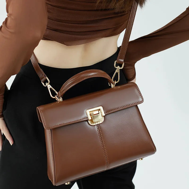 Women's black genuine leather shoulder bag with vachette clasp closure showing internal compartments