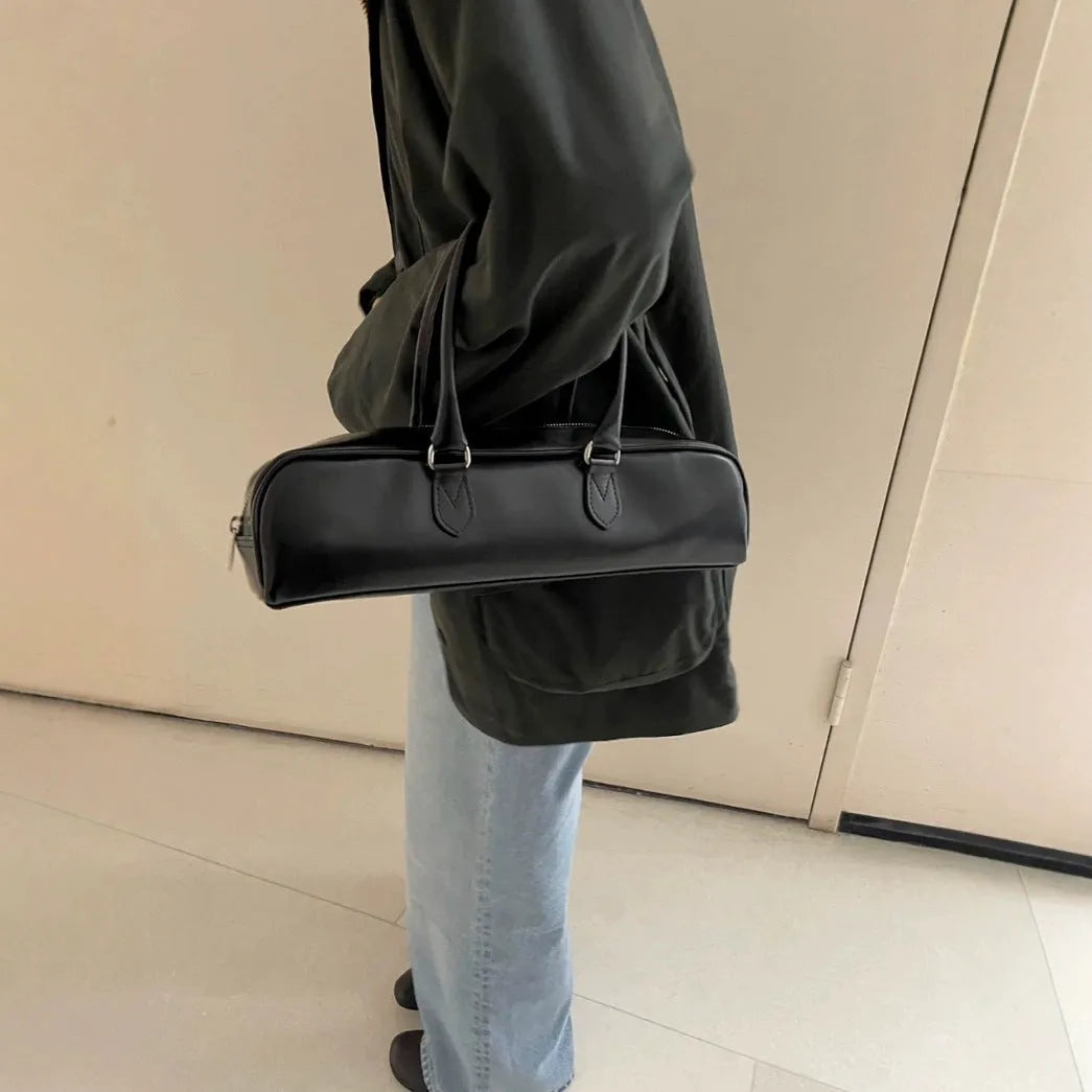 Black corduroy cowhide french stick underarm bag with sewing thread detail on a white background