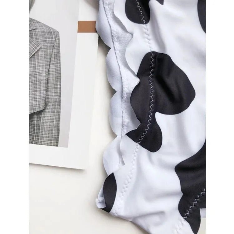 Women's black and white cow print bikini swimsuit with wrapped breast design on display