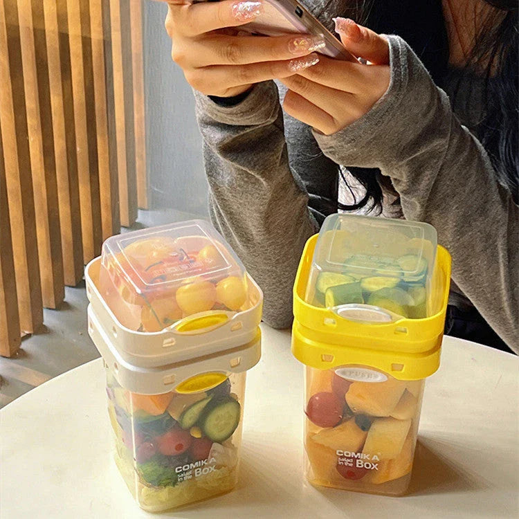 A portable bento box with two compartments for storing different types of food, such as salad, yogurt, oatmeal, and milkshake.