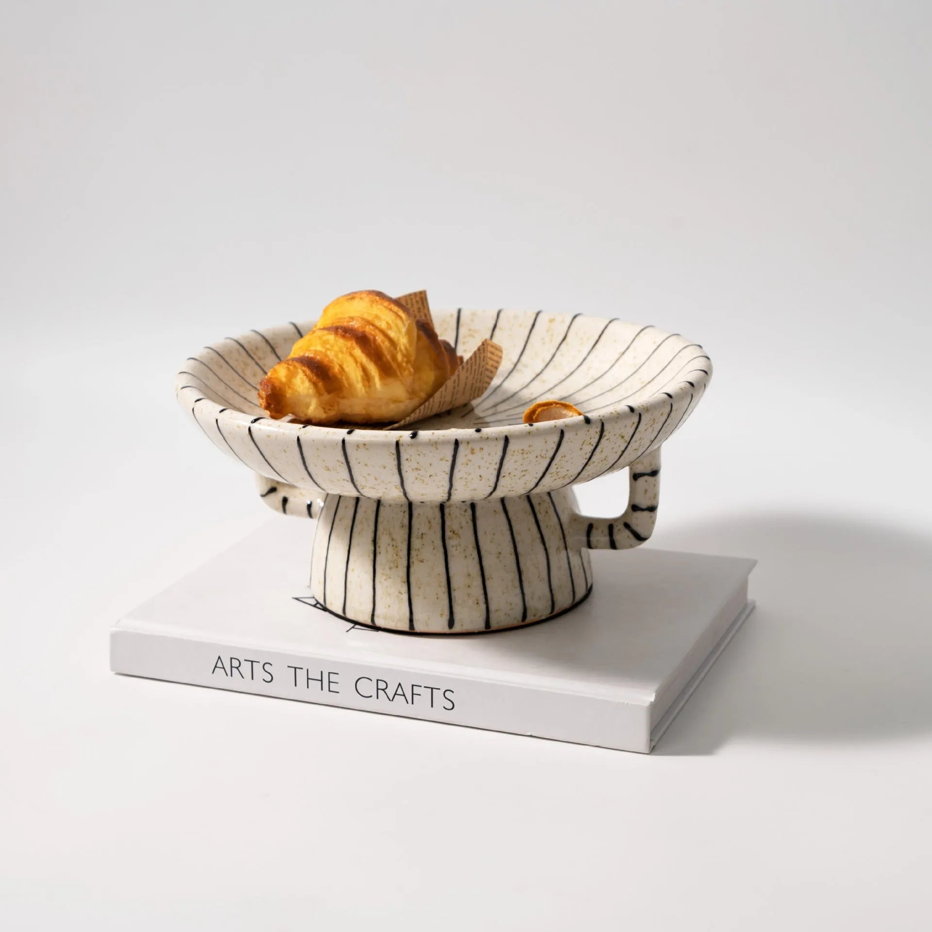 Black and white striped synthetic resin fruit plate on a plain surface.